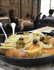 Bacalhau à lagareiro com cebola e azeitonas numa frigideira de ferro
